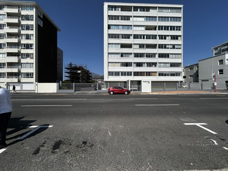 Street view of the Fortuna apartment building facade, featuring a multi-story residential structure with secure perimeter fencing and gated access.
