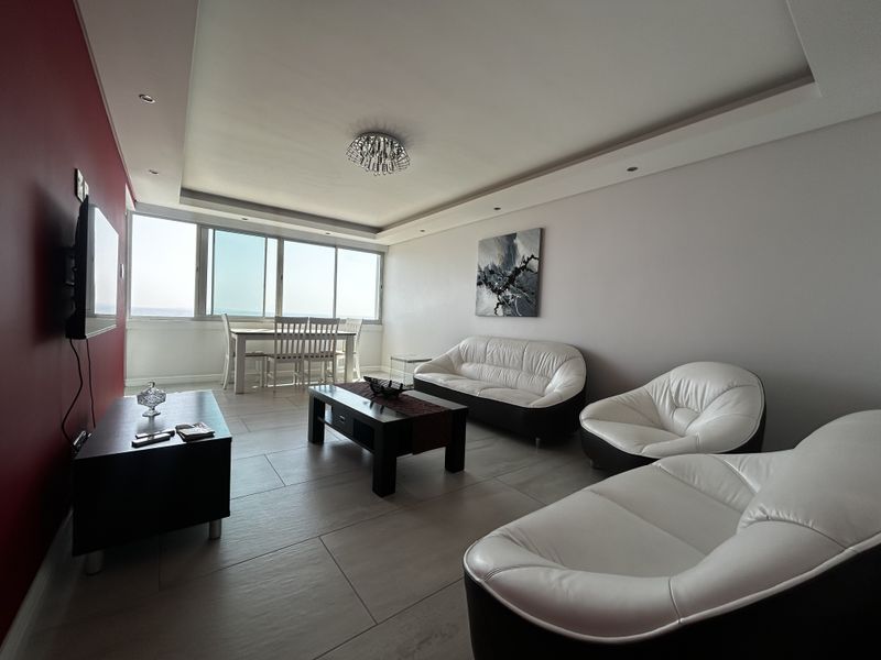 Spacious open-plan living and dining area featuring tiled floors, recessed ceiling lighting, and large sliding glass doors with natural light.