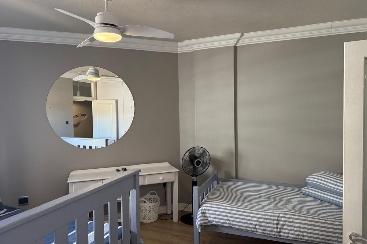A bedroom featuring neutral wall tones, crown molding, and a ceiling fan, providing a functional and well-lit living space.