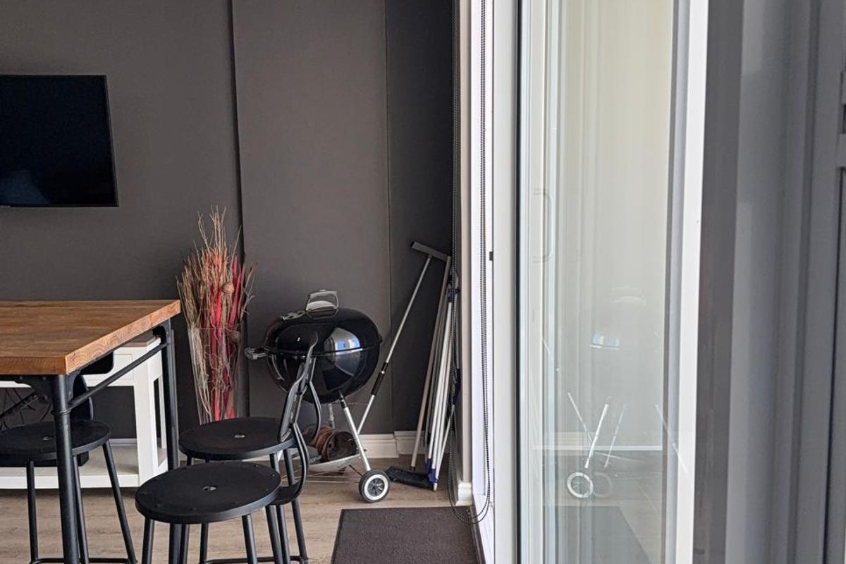 A modern living area featuring dark accent walls, crown molding, and large sliding glass doors that provide access to the outdoor space.