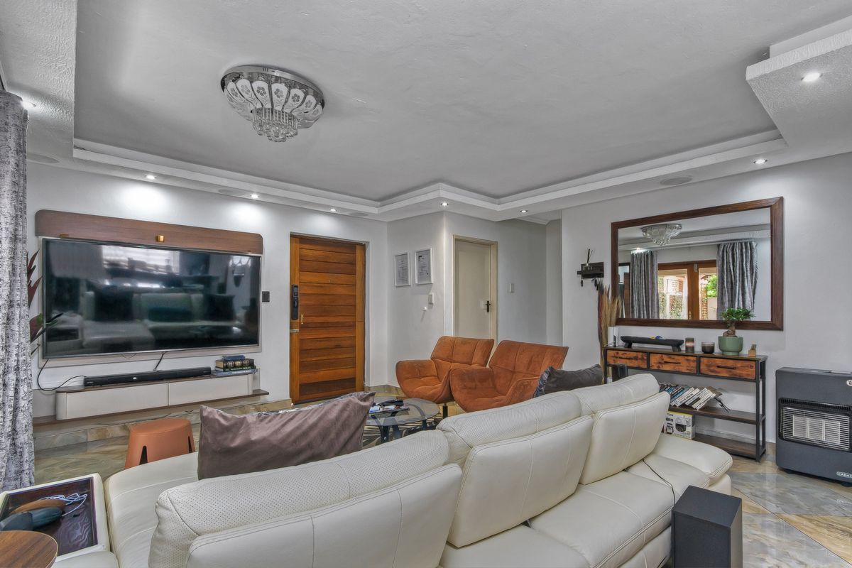 Spacious living room featuring recessed ceiling lighting, decorative crown molding, tiled flooring, and a built-in media wall unit.
