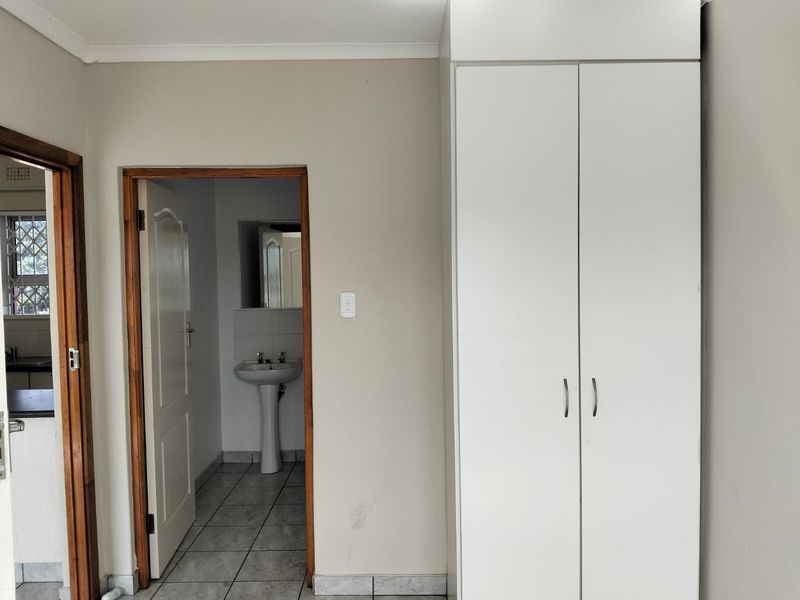 A bedroom featuring a built-in wardrobe and direct access to an en-suite bathroom with a pedestal basin and tiled flooring.