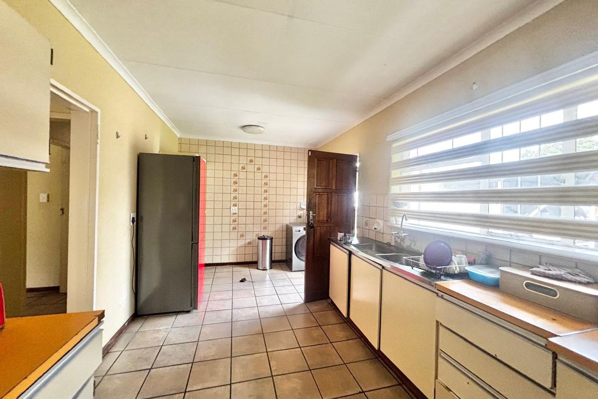 A functional kitchen featuring tiled flooring, built-in cabinetry, a double sink, and a large window providing natural light.