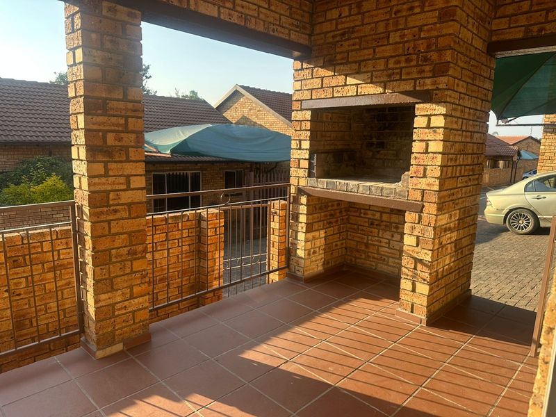 Covered patio area featuring a built-in brick braai, tiled flooring, and brick structural pillars, offering a functional outdoor entertainment space.