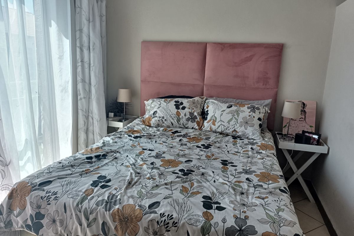 A well-lit bedroom featuring tiled flooring and a large sliding glass door providing natural light.