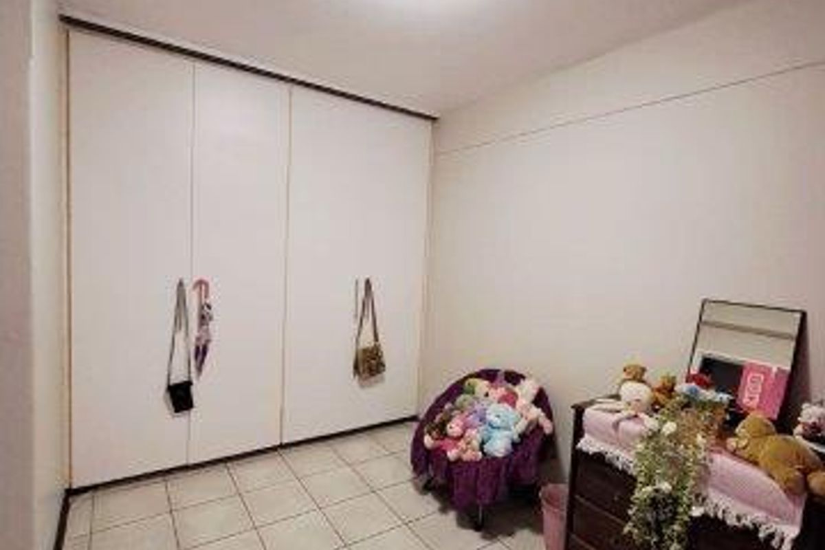 A bedroom featuring tiled flooring and built-in cupboards, offering a functional space with neutral finishes.