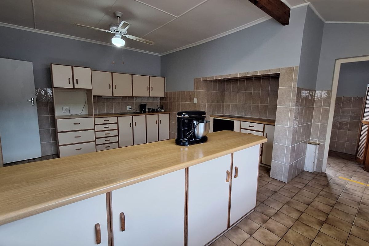 A functional kitchen featuring a central island, tiled flooring, and ample built-in cabinetry with a tiled splashback area.