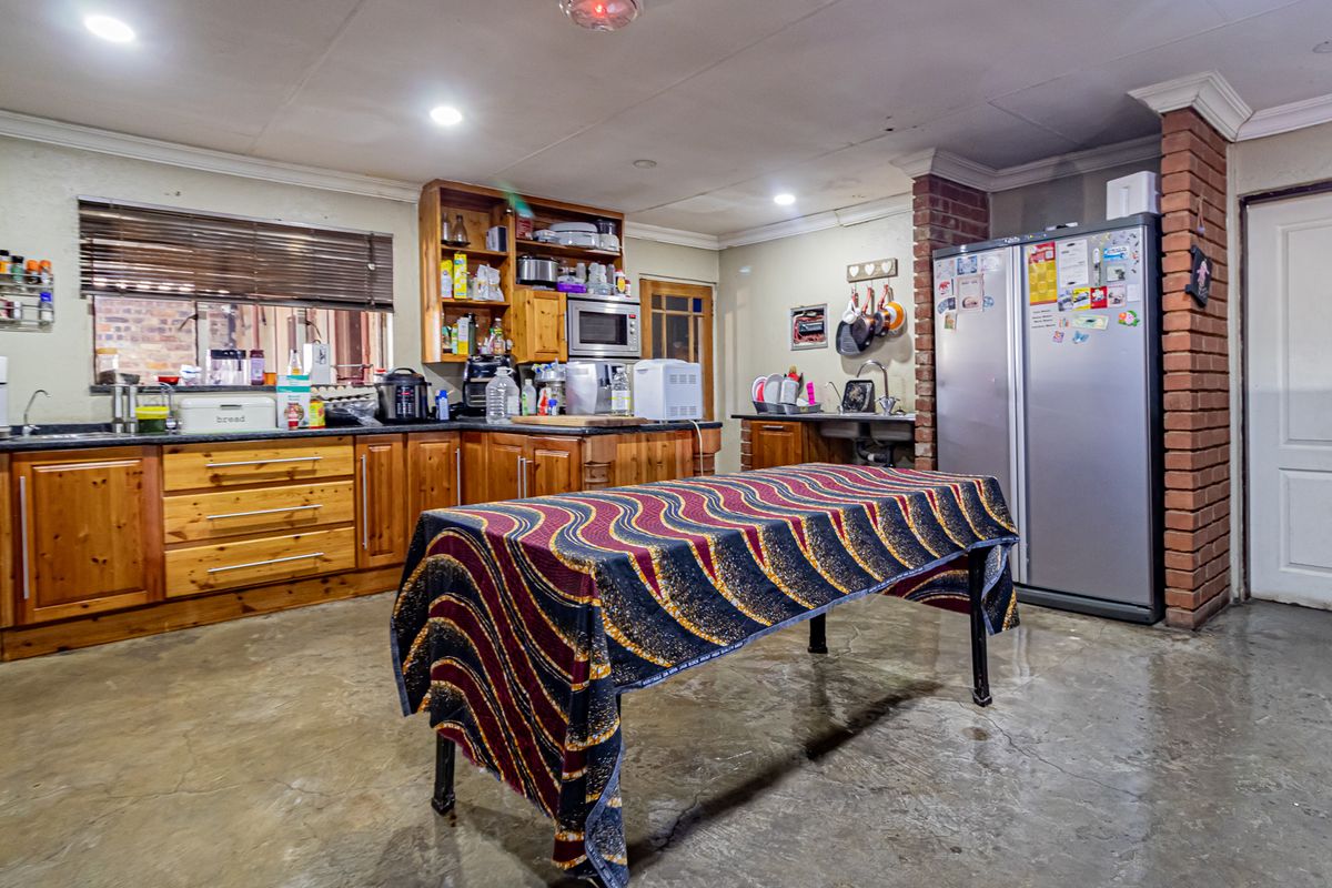 Spacious kitchen featuring wooden cabinetry, exposed brick accents, and concrete flooring, offering a functional layout with ample storage and preparation space.