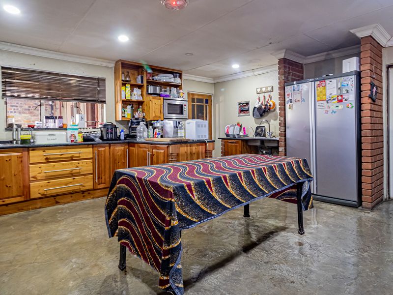 Spacious kitchen featuring wooden cabinetry, exposed brick accents, and concrete flooring, offering a functional layout with ample storage and preparation space.