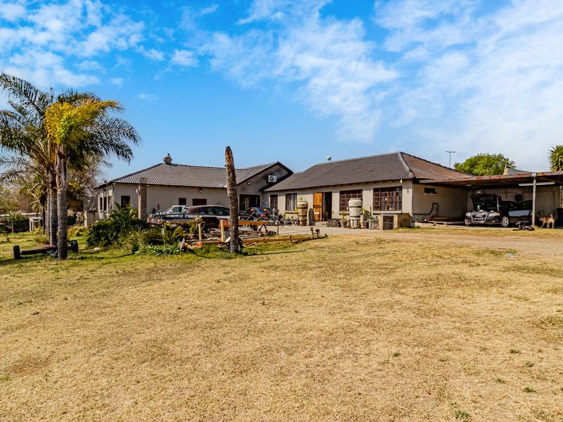 Rear view of the small holding property featuring a tiled roof dwelling, attached carport, and expansive grounds.