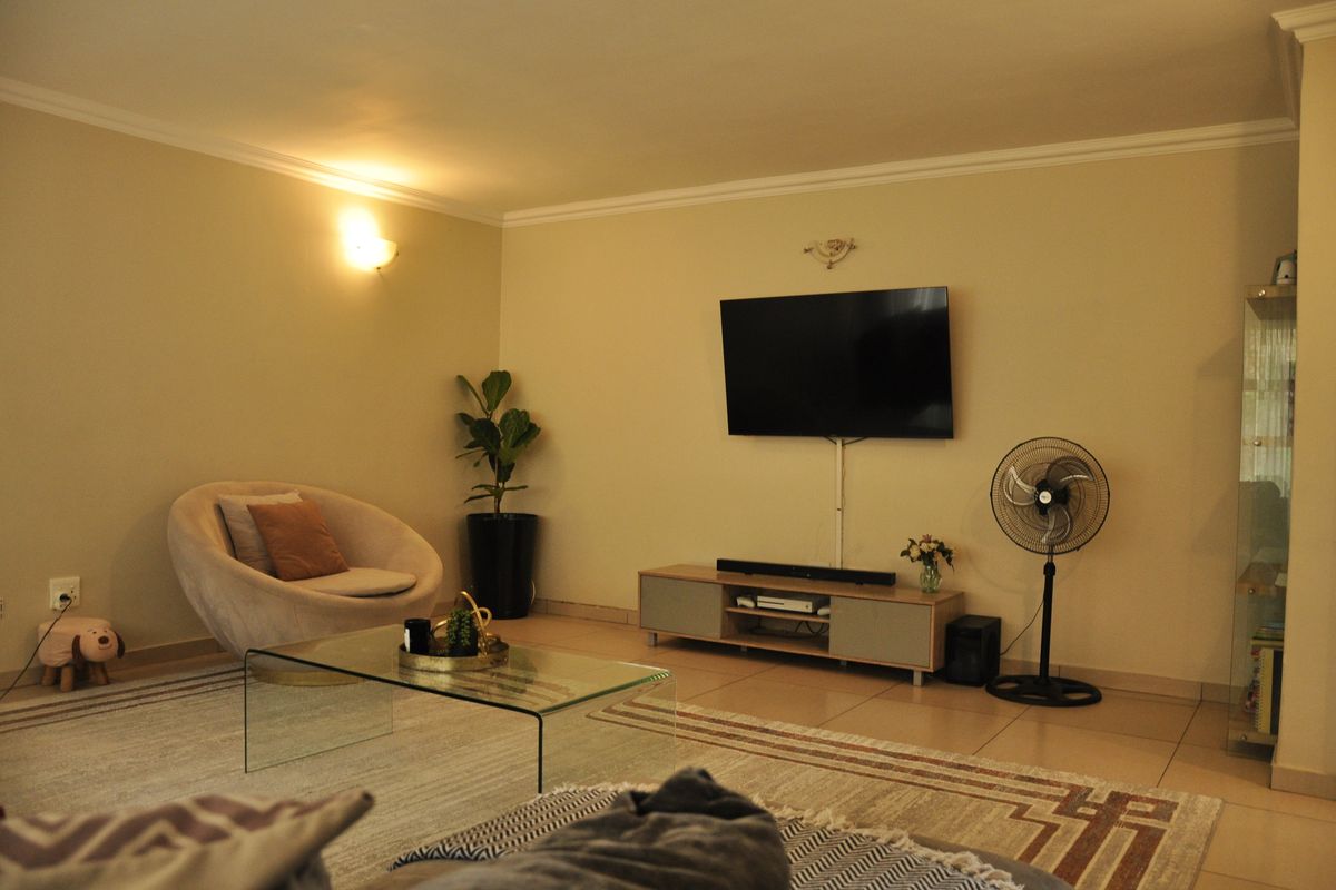 A comfortable living room featuring tiled flooring, neutral wall tones, and decorative cove cornicing, providing a functional and inviting space for relaxation.