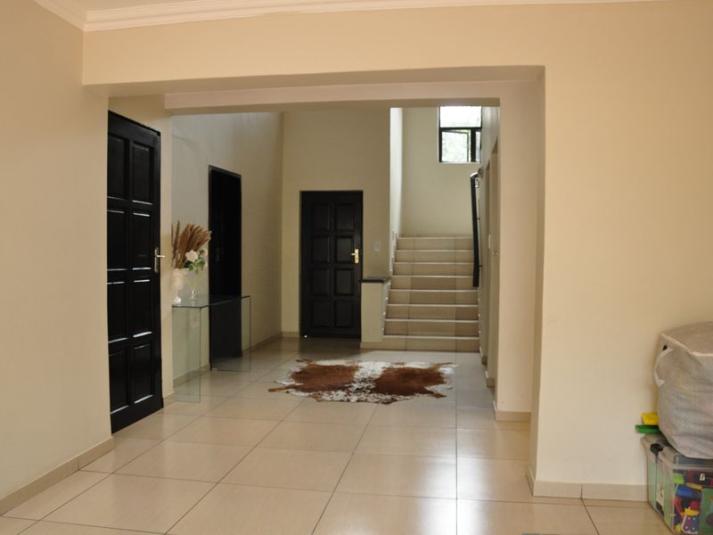 Spacious entrance hallway featuring tiled flooring and a staircase leading to the upper level, providing a clean and neutral foundation for the home.
