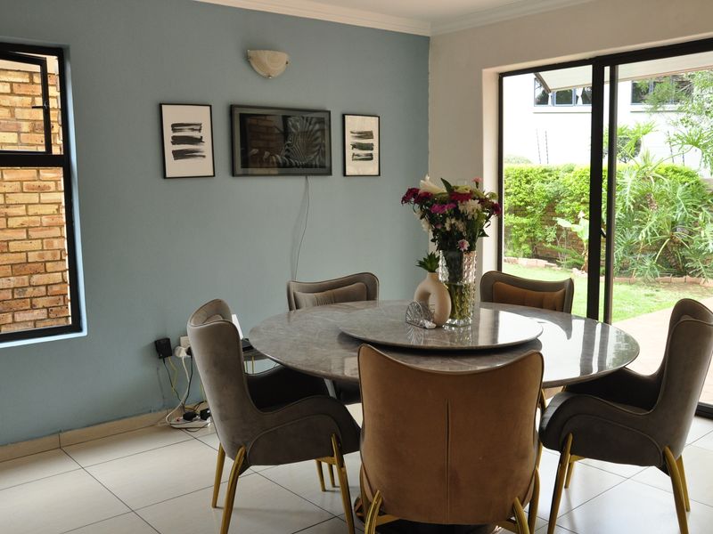 A bright dining area featuring tiled floors, a wall sconce, and large sliding glass doors providing direct access to the garden.