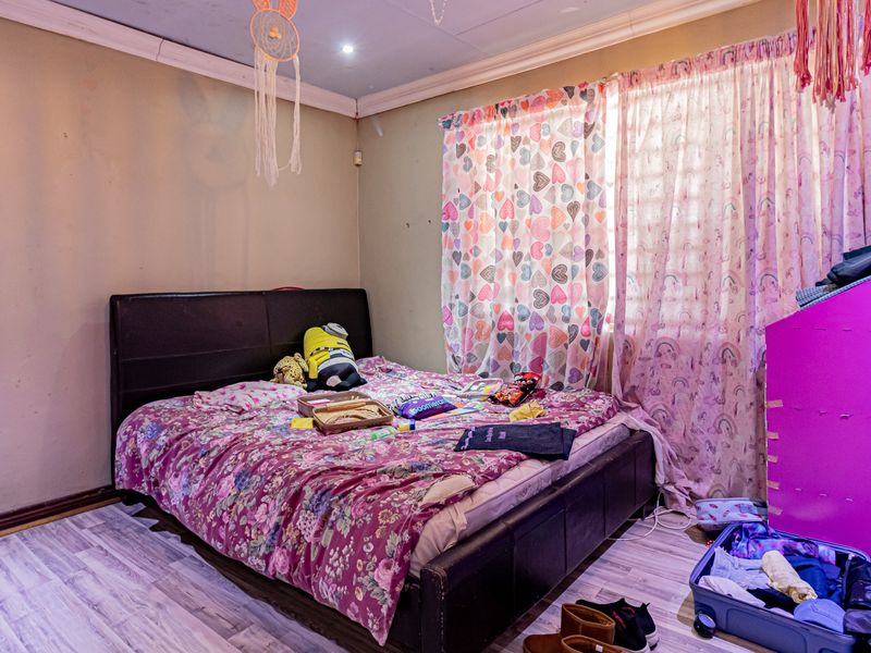 A bedroom featuring laminate flooring, coved ceilings, and recessed lighting, currently showing signs of wear on the wall surfaces.