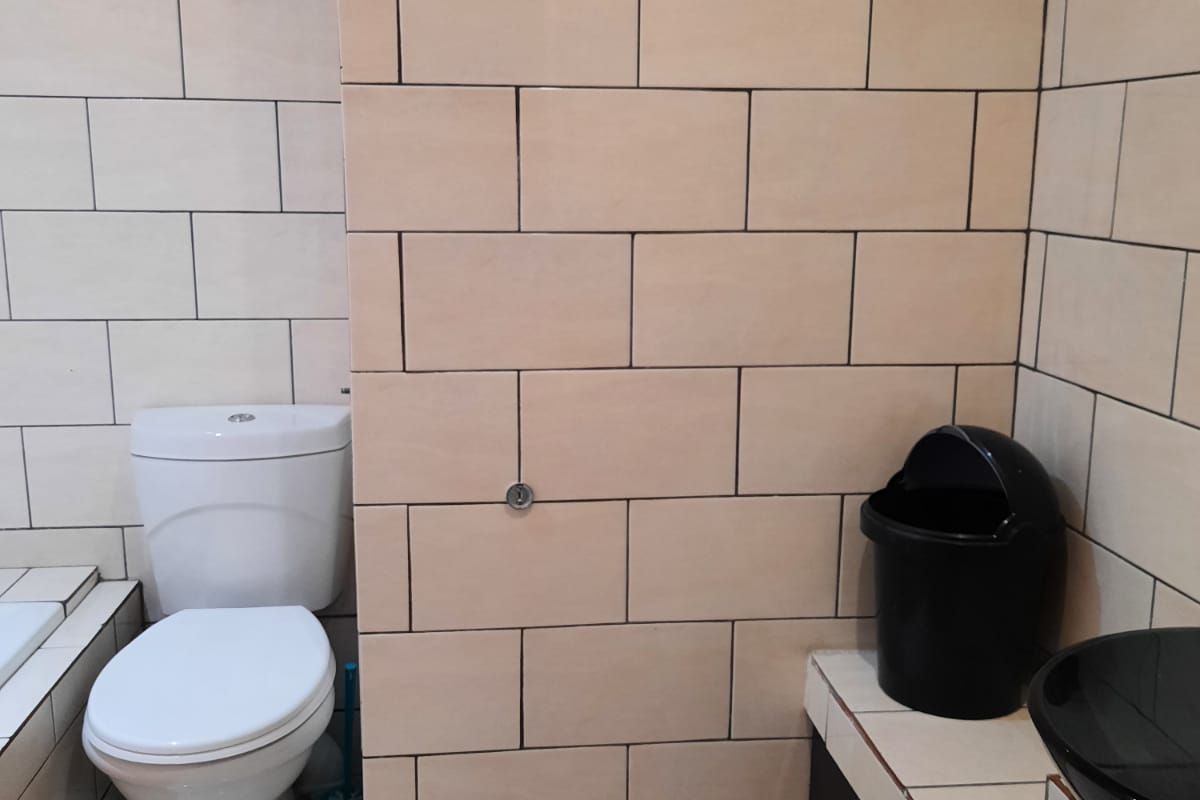 A functional bathroom featuring tiled walls, a standard toilet, and a vanity unit with a vessel sink.