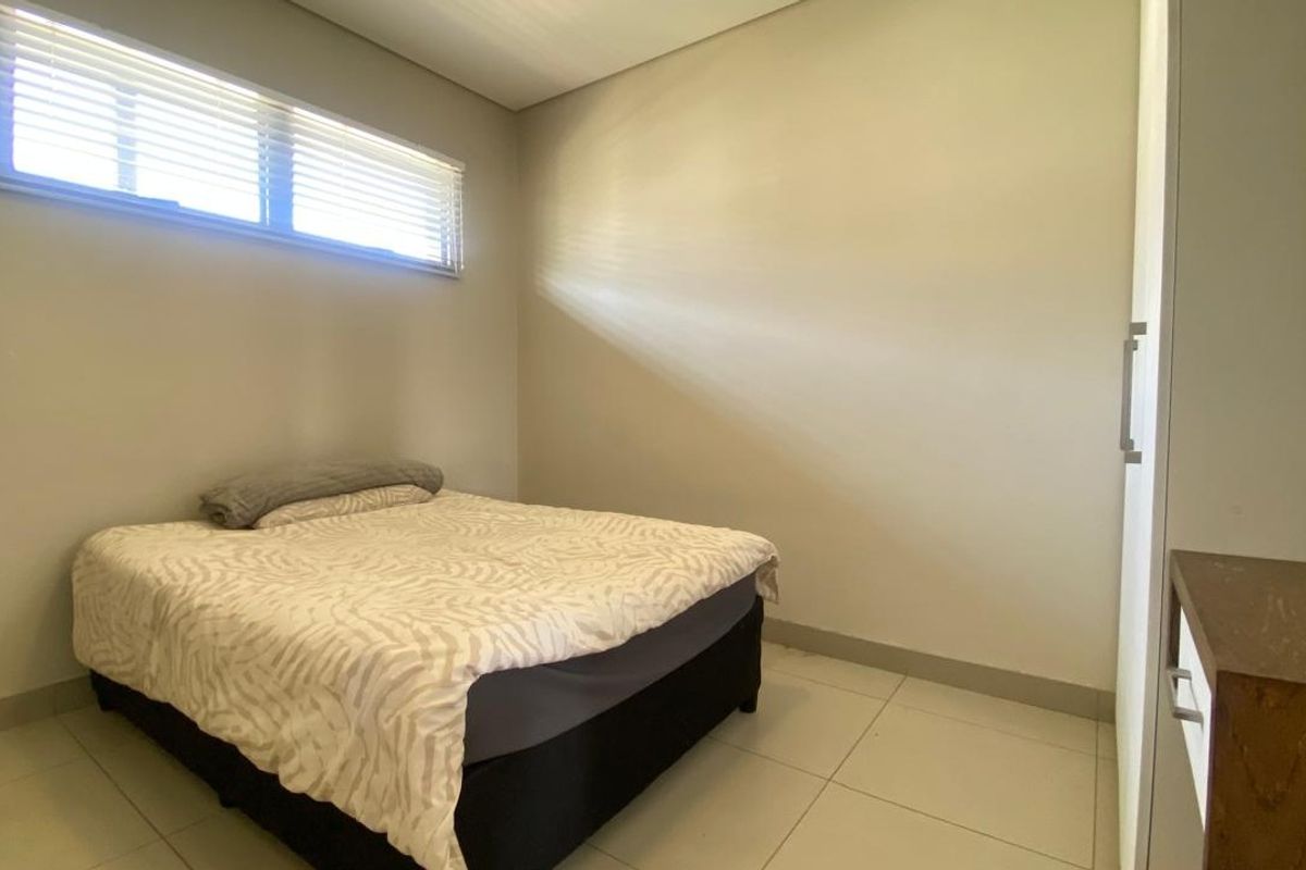 A bedroom featuring tiled flooring, a horizontal window with fitted blinds, and built-in cabinetry.