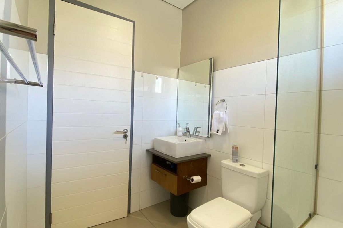 Modern bathroom featuring a floating vanity with a vessel sink, a glass-enclosed shower, and a wall-mounted toilet.