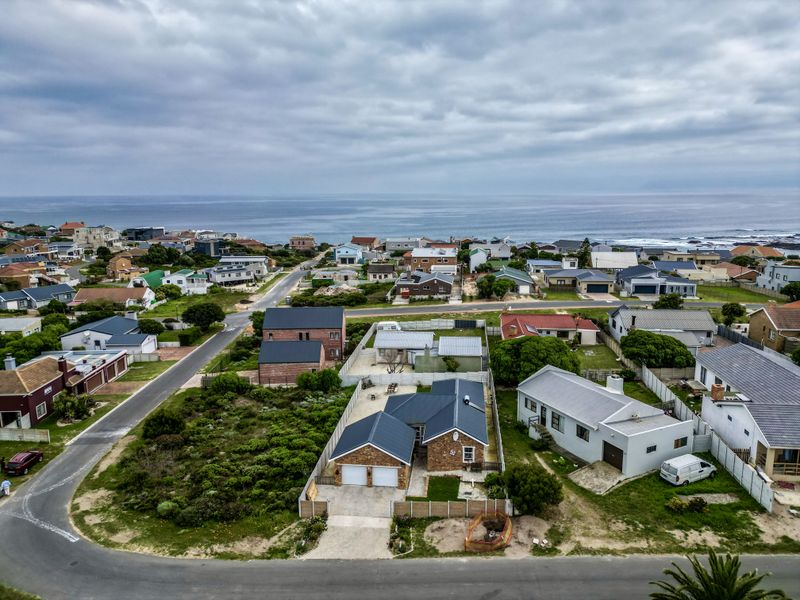 Aerial view of a coastal residential neighborhood featuring detached houses, paved streets, and proximity to the ocean.