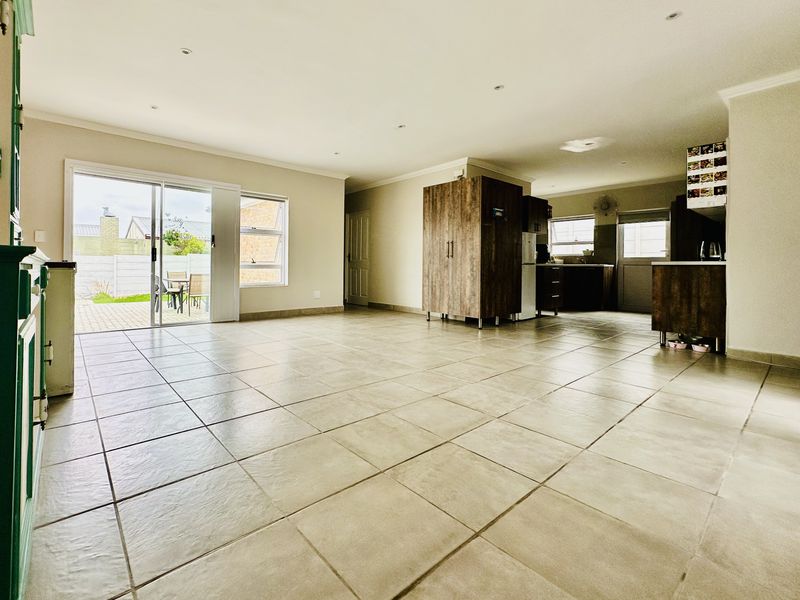Spacious open-plan living and kitchen area featuring neutral tiled flooring, recessed lighting, and direct access to the rear patio through sliding glass doors.