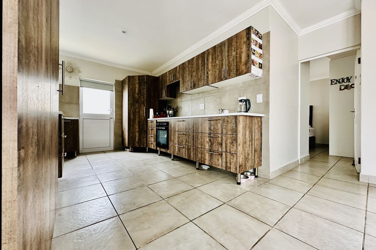 A functional kitchen featuring wood-grain cabinetry, tiled flooring, and a built-in oven, offering a clean and practical workspace.