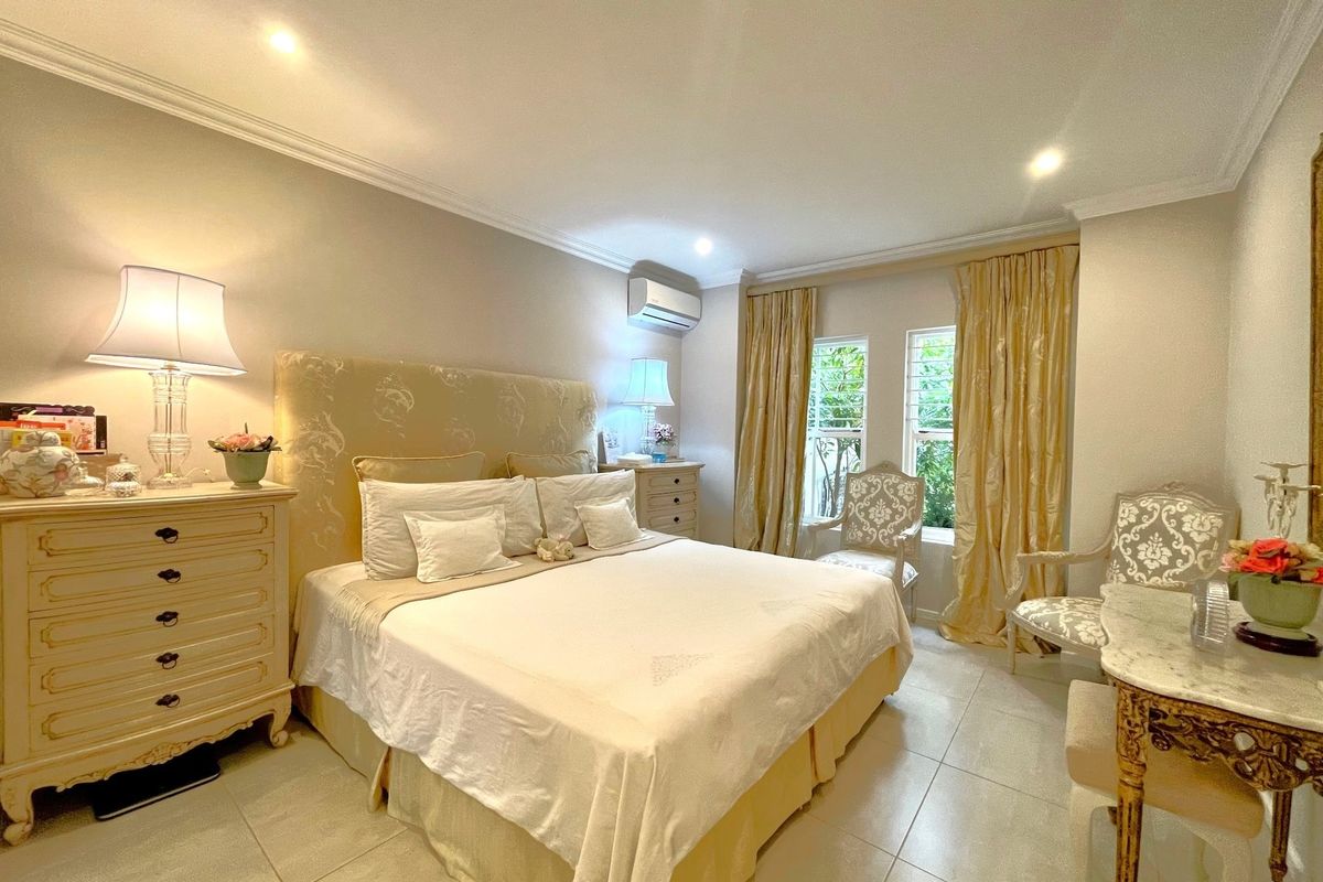 A well-maintained bedroom featuring tiled flooring, crown molding, and a wall-mounted air conditioning unit.