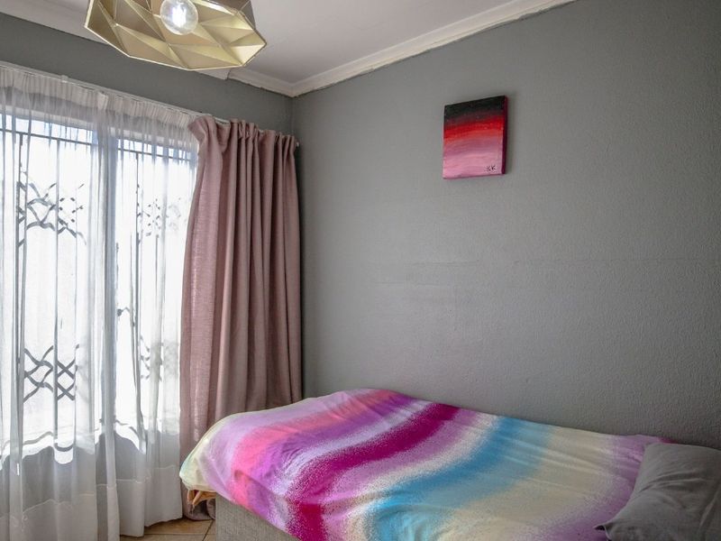 A bedroom featuring a window with security bars and a central ceiling light fixture.