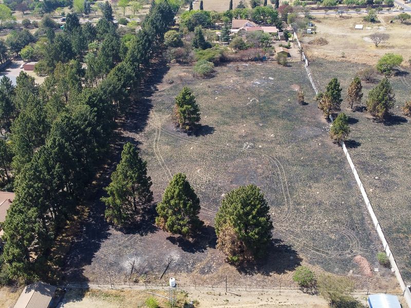 Aerial view of a large plot of land featuring perimeter fencing and boundary walls, showing signs of recent fire damage to the vegetation.