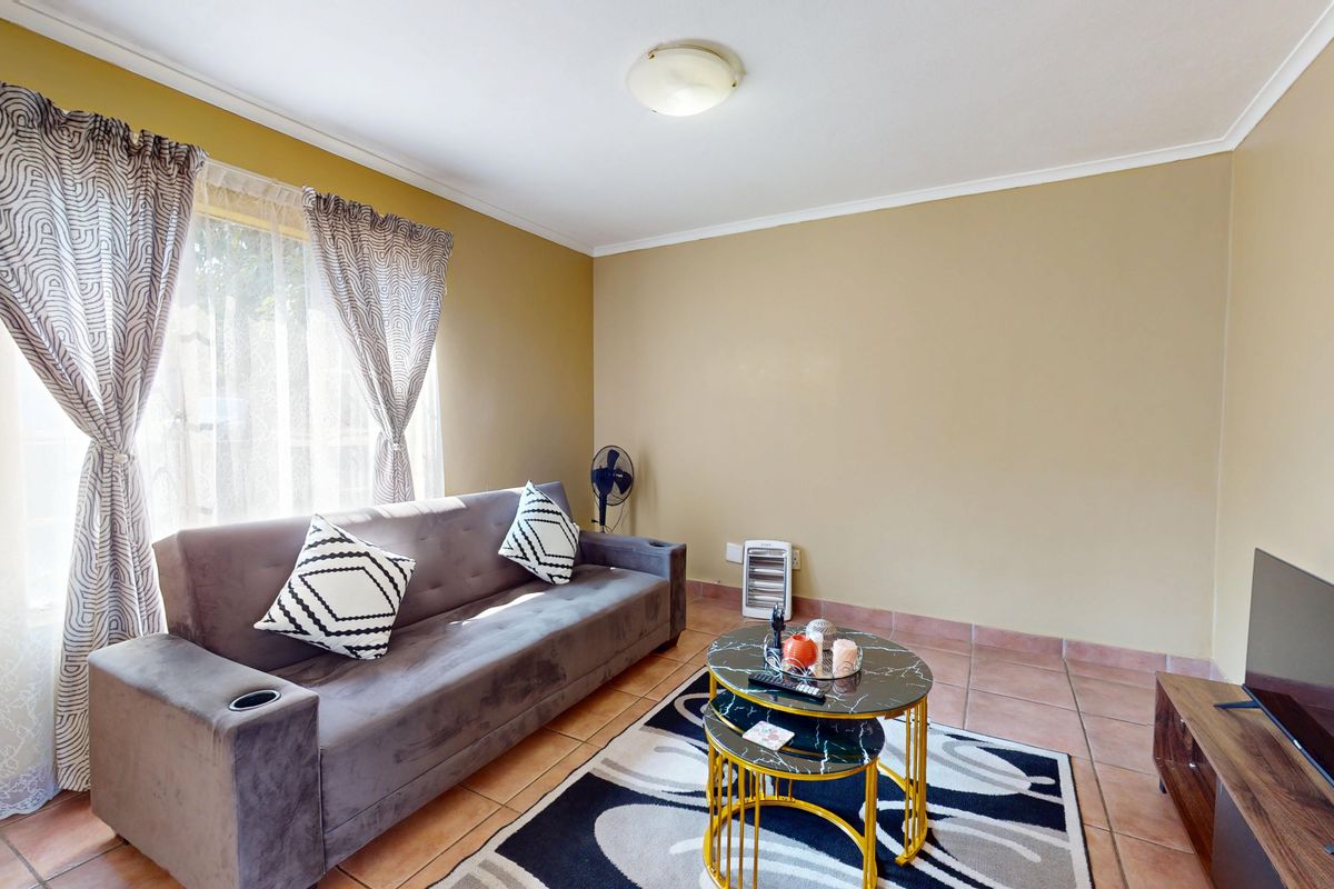 A functional living room featuring tiled flooring and neutral wall tones, providing a comfortable and practical space for relaxation.