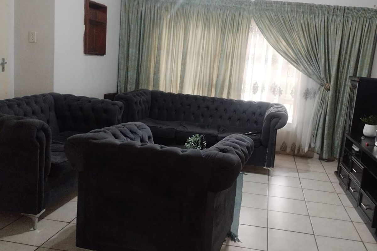 A living room featuring tiled flooring and large window treatments, providing a functional and comfortable space for relaxation.