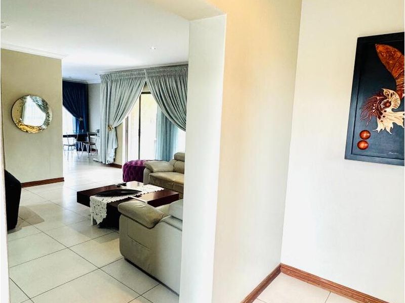 A view from the hallway into an open-plan living area featuring tiled flooring, neutral wall tones, and large sliding doors leading to the exterior.