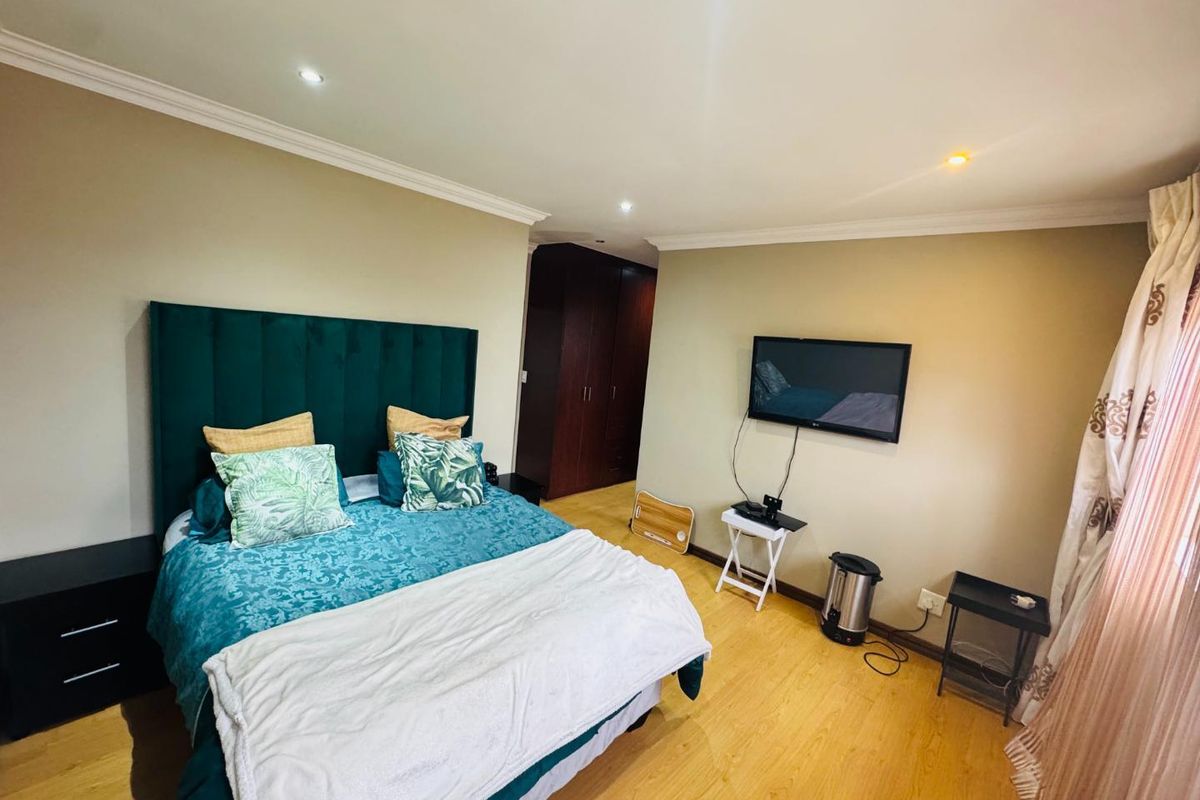 A well-maintained bedroom featuring laminate flooring, recessed ceiling lighting, and built-in dark wood cabinetry.