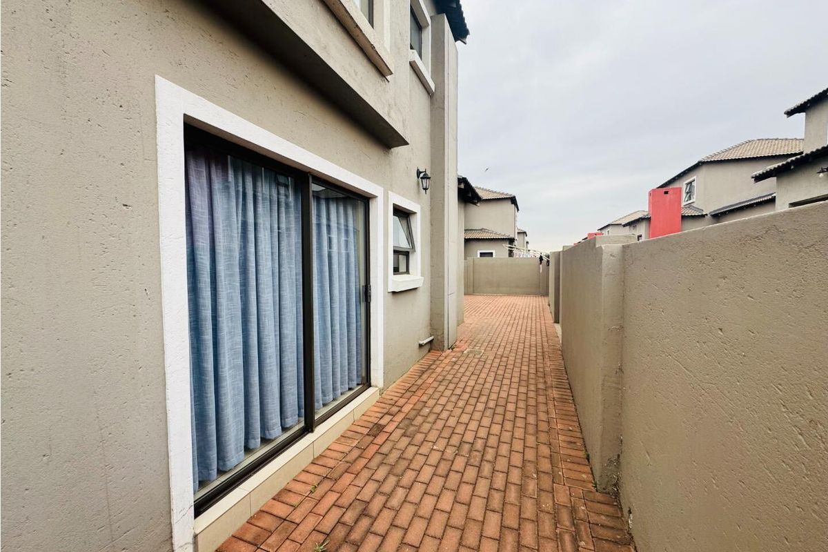 A side exterior walkway featuring paved flooring and access to the home via sliding glass doors, enclosed by boundary walls.