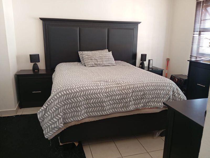 A functional bedroom featuring tiled flooring and window blinds, providing a neutral base for personal styling.