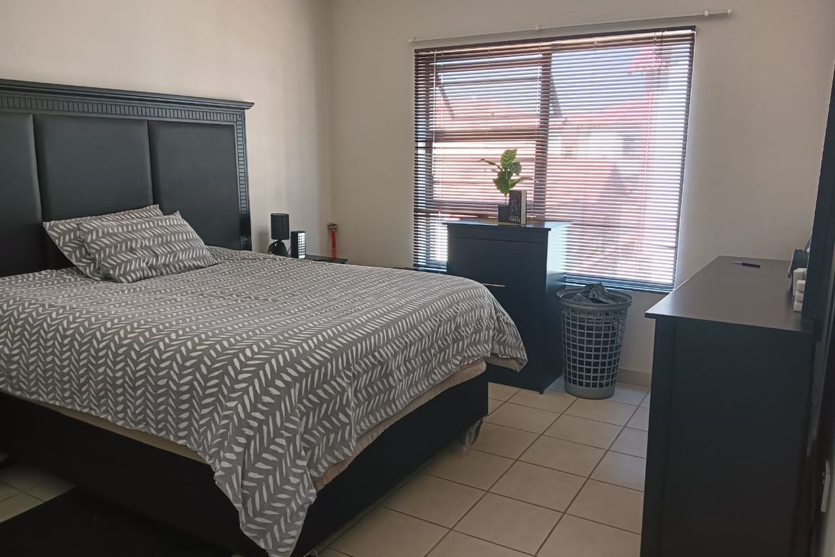 A functional bedroom featuring tiled flooring and venetian blinds, providing a neutral base for personal styling.