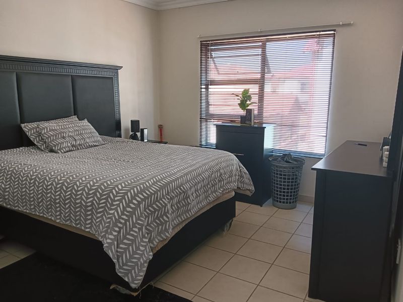A functional bedroom featuring tiled flooring and venetian blinds, providing a neutral base for personal styling.