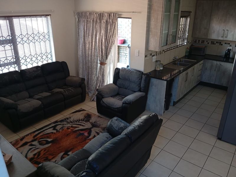 Open plan living area featuring tiled flooring and a functional kitchen with built-in cabinetry and double sink.