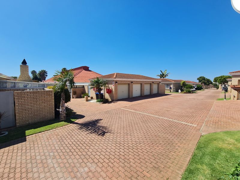 A wide-angle view of a townhouse complex driveway featuring multiple garage units, brick paving, and established exterior brickwork.