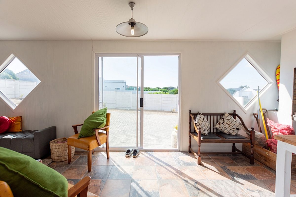 A bright living area featuring unique diamond-shaped windows, tiled flooring, and a sliding glass door providing direct access to the exterior patio.