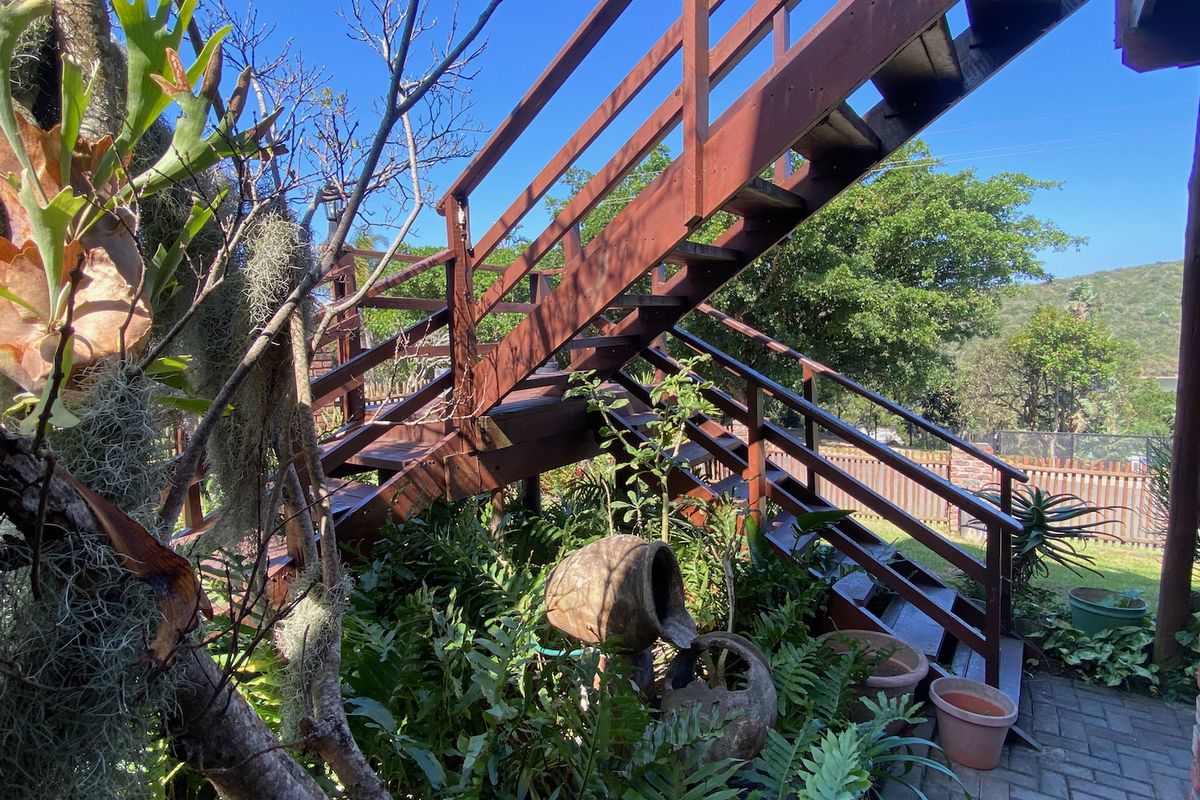 An outdoor wooden staircase leading to an upper level, set within a landscaped garden area with paved pathways.