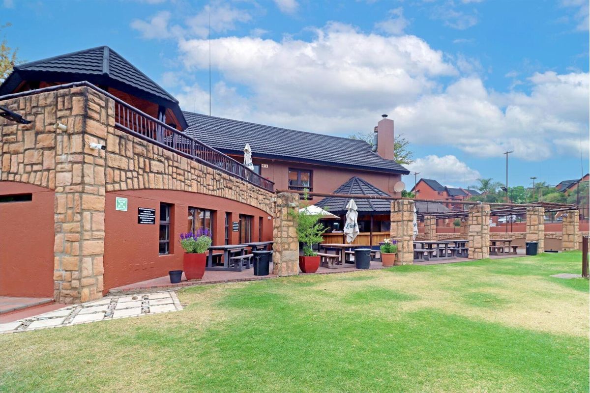 Exterior view of the apartment complex featuring a paved patio area, stone-clad pillars, and a well-maintained lawn.