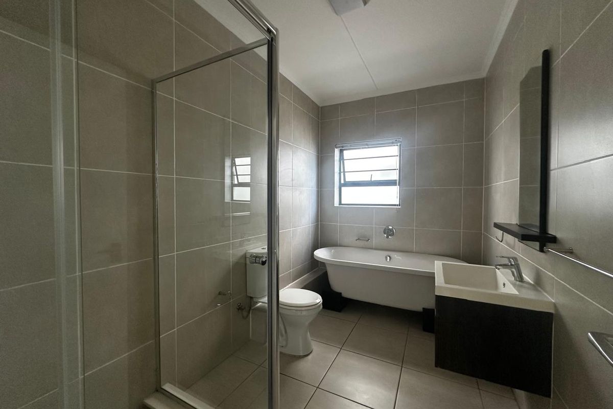 A modern, well-maintained bathroom featuring a freestanding bathtub, a separate glass-enclosed shower, and a sleek wall-mounted vanity with neutral tiling throughout.