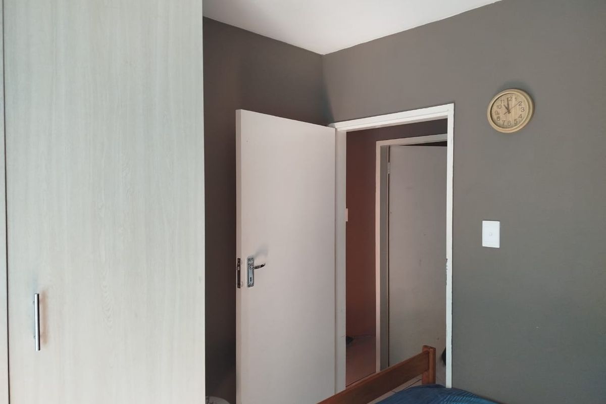 A bedroom interior featuring a built-in wardrobe with light wood-grain finish and dark grey painted walls.