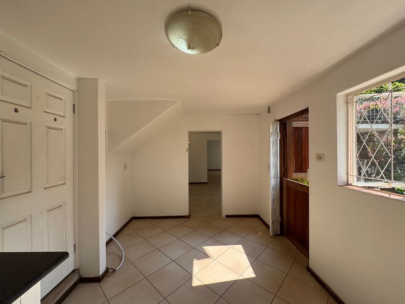 An empty entrance area featuring tiled flooring, a stable door, and a window with security grille, leading into the interior of the cottage.