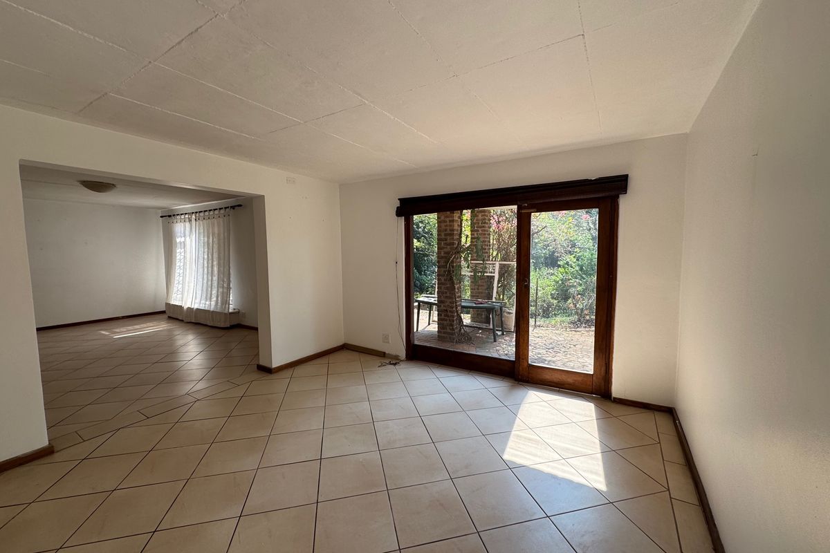 An empty, open-plan living area featuring tiled flooring and a sliding glass door providing access to the rear garden.