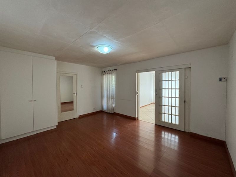 An empty bedroom featuring laminate flooring, a built-in wardrobe, and a glass-paneled door leading to an adjacent space.