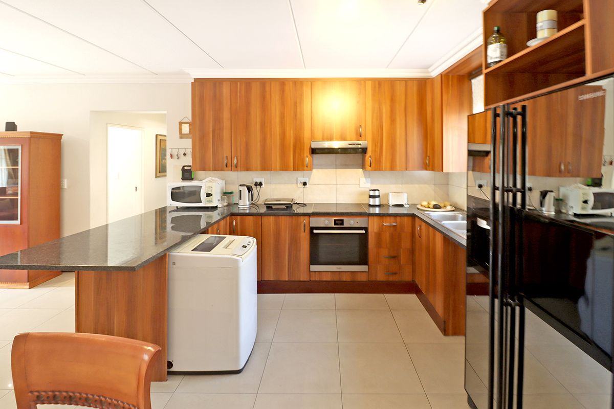 A functional kitchen featuring wood-finish cabinetry, granite countertops, a built-in oven, extractor fan, and tiled flooring.