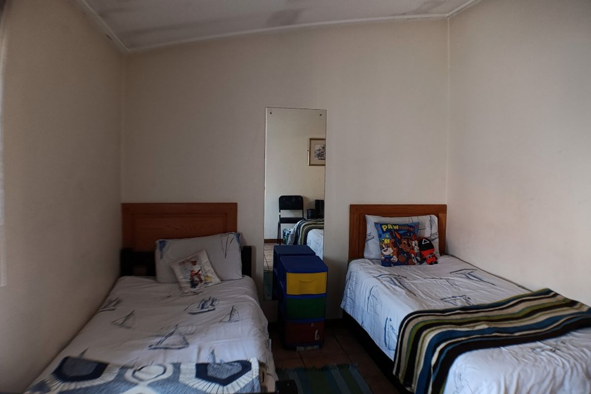 A functional bedroom featuring tiled flooring and a wall-mounted mirror, providing a practical space for residents.