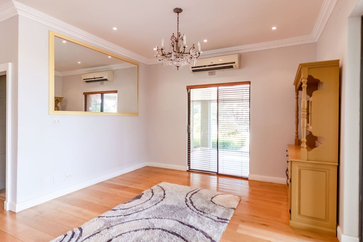 Bright living room featuring hardwood flooring, crown molding, recessed lighting, a crystal chandelier, and sliding glass doors leading to the outdoor area.
