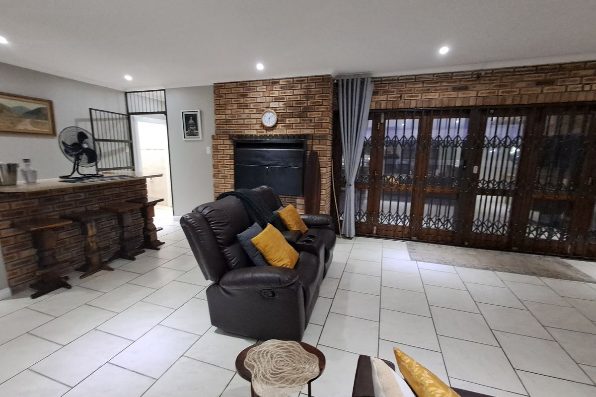 Spacious living room featuring a brick fireplace, built-in bar area, and tiled flooring, providing a functional and character-filled entertainment space.