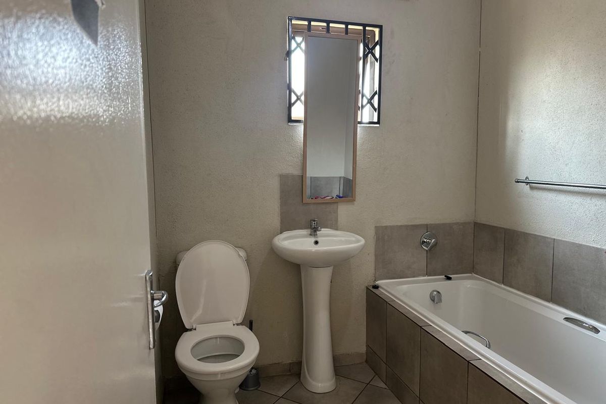 A functional bathroom featuring a pedestal basin, a standard bathtub with tiled surround, and a toilet.